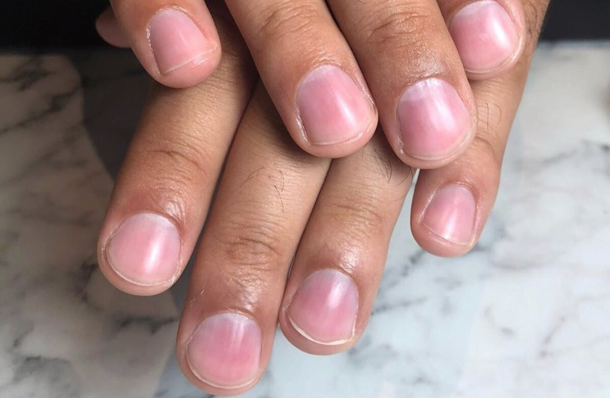 Close-up of hands with pink nail polish on a marble surface